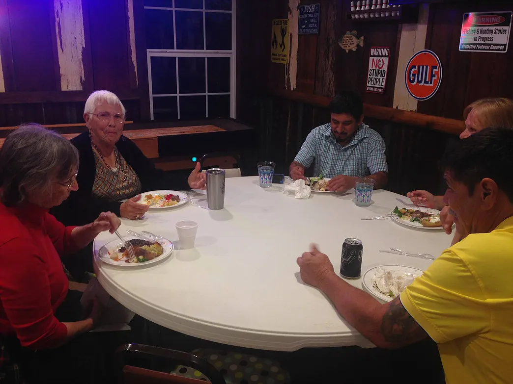 Guests sharing a meal around a round table inside the Amigo Inn recreation hall