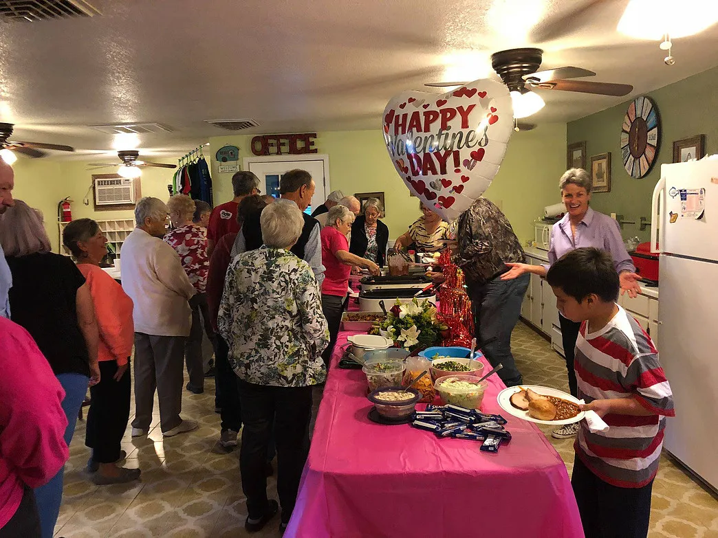 Guests lining up for a buffet meal with a Valentine's Day balloon in the Amigo Inn recreation hall