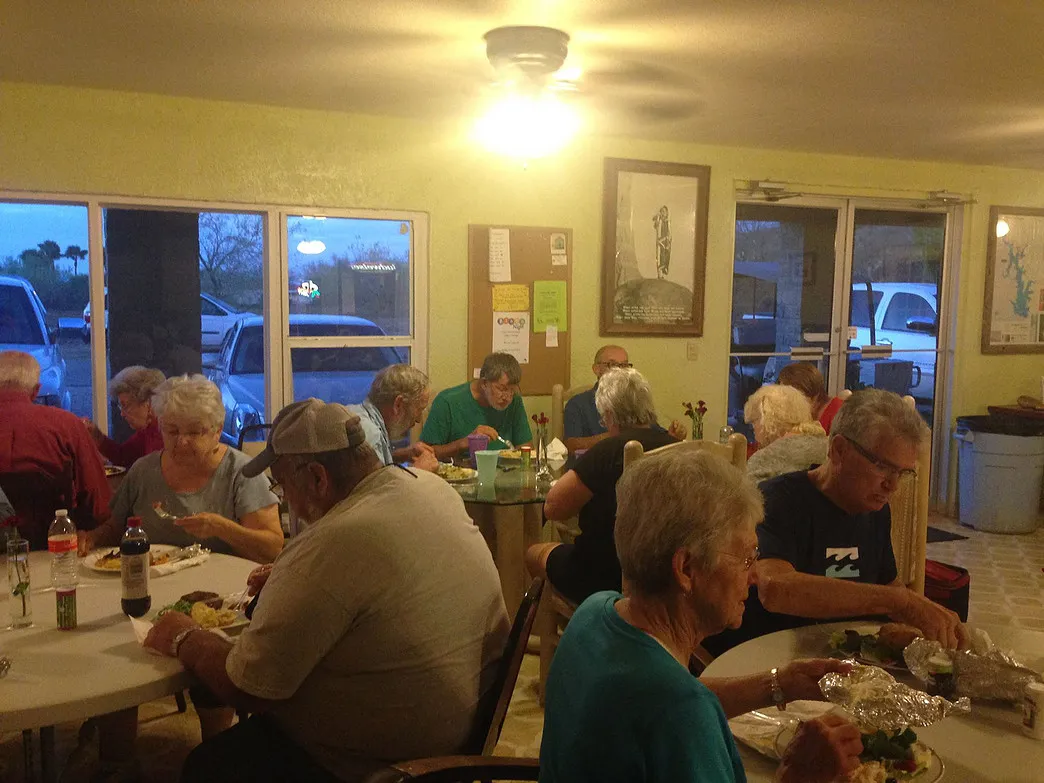 Guests sharing an evening meal at round tables inside the Amigo Inn recreation hall