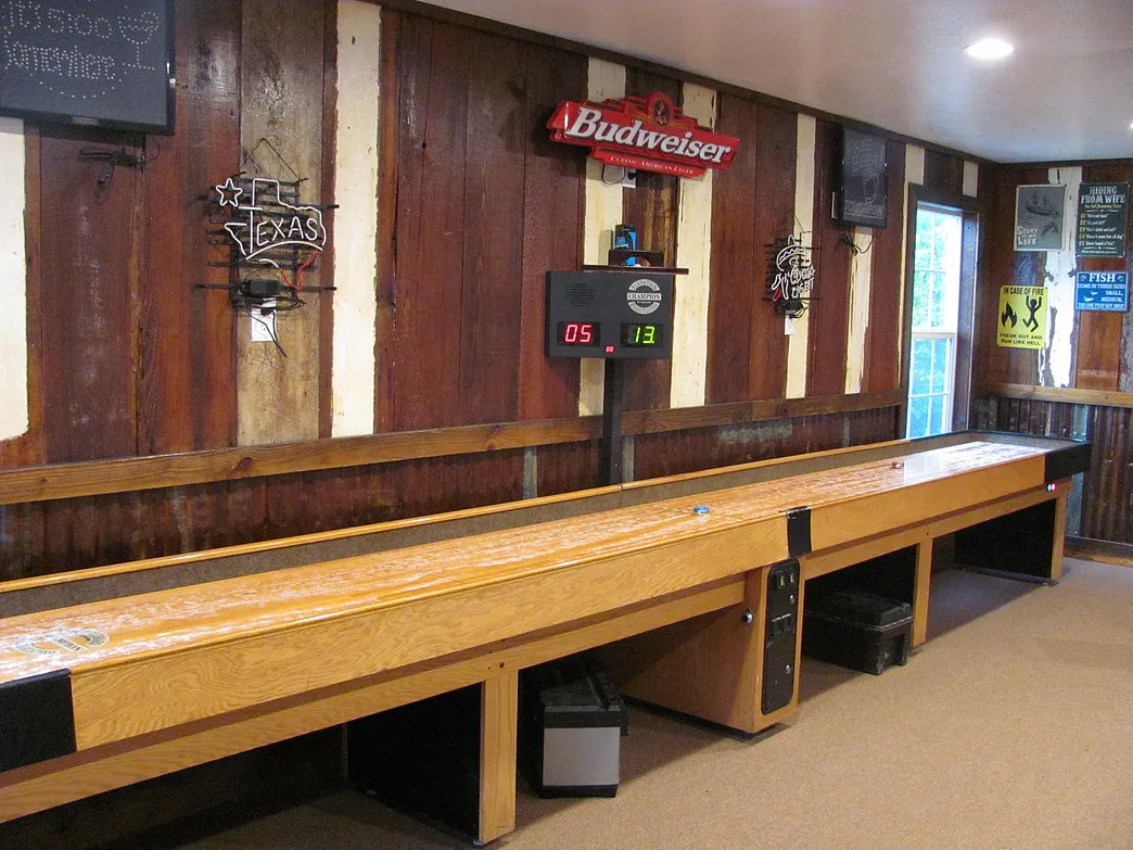 Long wooden shuffleboard table with a digital scoreboard in the Amigo Inn recreation room