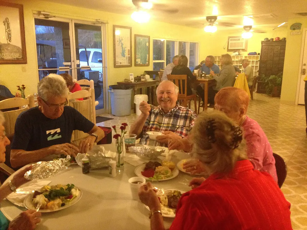 Guests sharing a community meal and conversation inside the Amigo Inn recreation hall